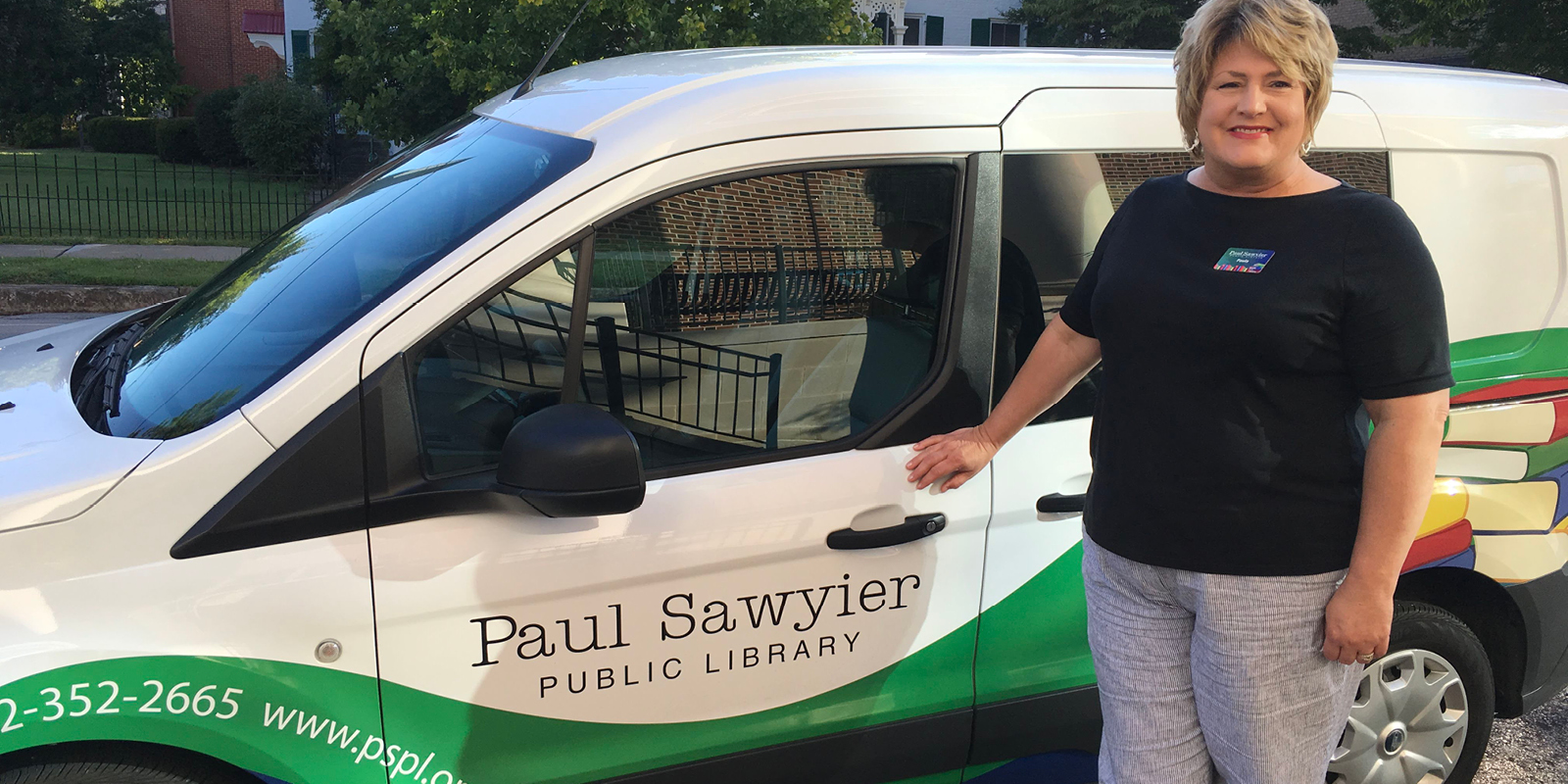 Librarian smiling and standing in from of the Paul Sawyier Public Library Van
