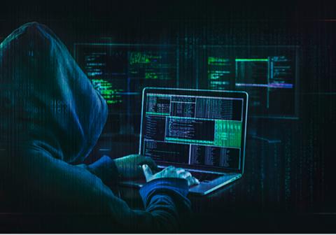 Person wearing a hooded sweatshirt working on a laptop computer